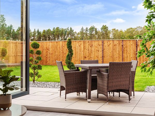A four seater garden table viewed from open bifold doors in a modern Charles Church new build home. 