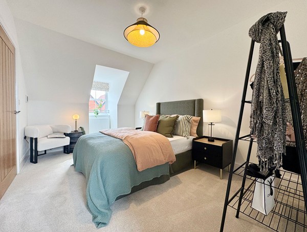 Spacious main bedroom in a modern new‑build home at Westwood, Curbridge, featuring a double bed with upholstered headboard, neutral décor, soft carpet and a large window.