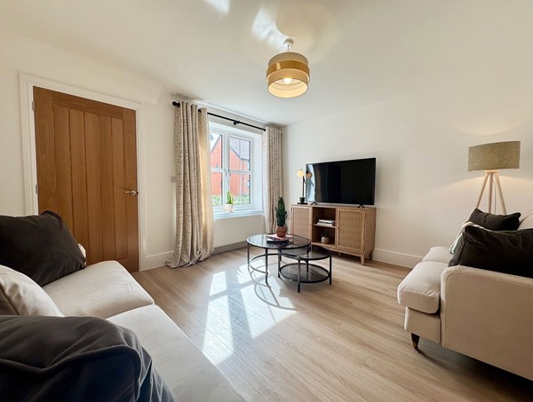 Light and airy living room in a modern new‑build home at Westwood, Curbridge, with comfortable seating, wood‑effect flooring, a large window and contemporary furnishing