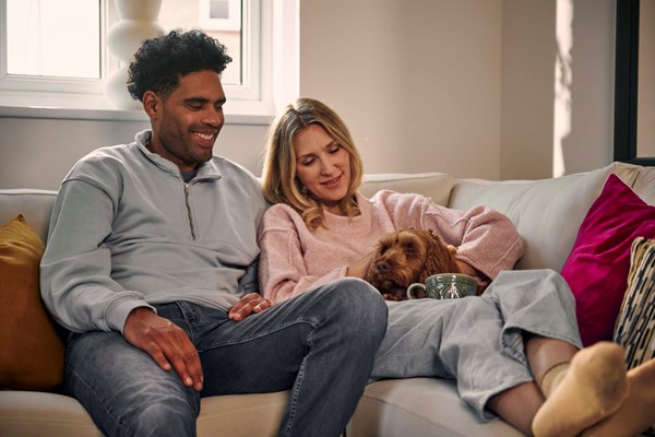 Smiling couple sitting on sofa with dog