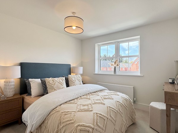 Double bedroom with neutral bedding, bedside tables and window
