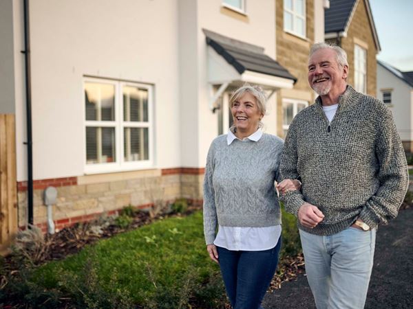 A man and a woman walking down a Charles Church street.
