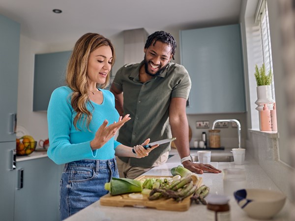 A young couple cooking in their new, modern Persimmon kitchen. 