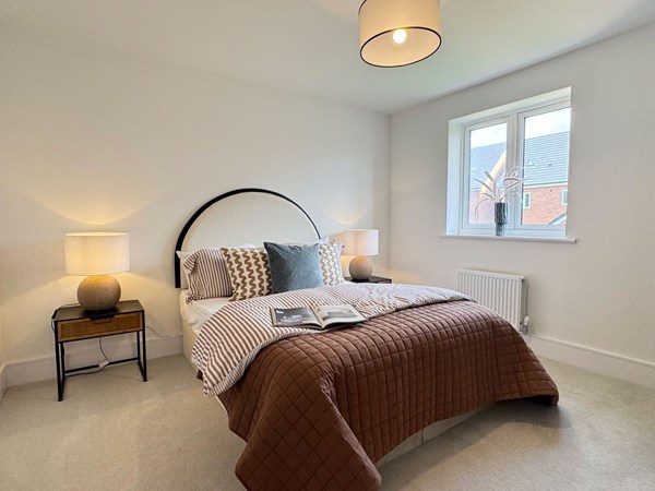 Double bedroom with patterned bedding, bedside tables and window
