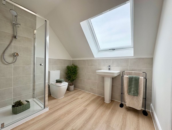 Modern shower room at Westwood, Curbridge, featuring a walk‑in shower, tiled walls, skylight window, pedestal sink and wood‑effect flooring.