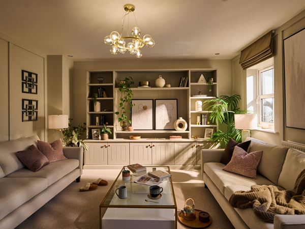 A Charles Church living room with modern cream sofas and dappled sunlight coming through the window.