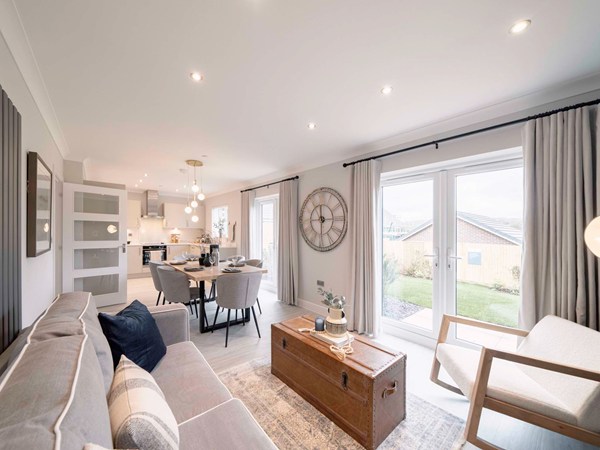 An interior photograph of a bright and modern Charles Church kitchen, dining and family room with French doors. 
