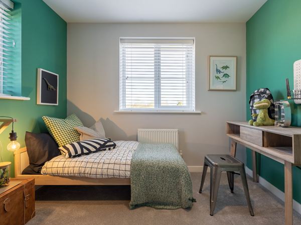 A boys bedroom in a modern Charles Church home with a teal wall and a study area.