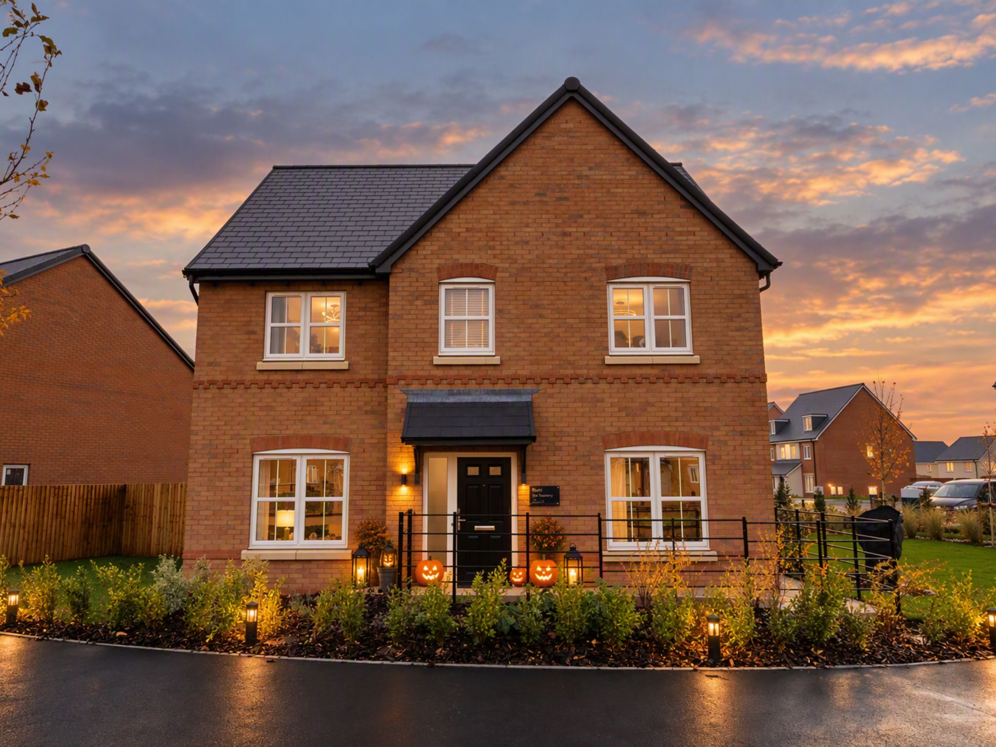 A new build home by Charles Church, the exterior decorated for Halloween with pumpkins and warm amber lighting.