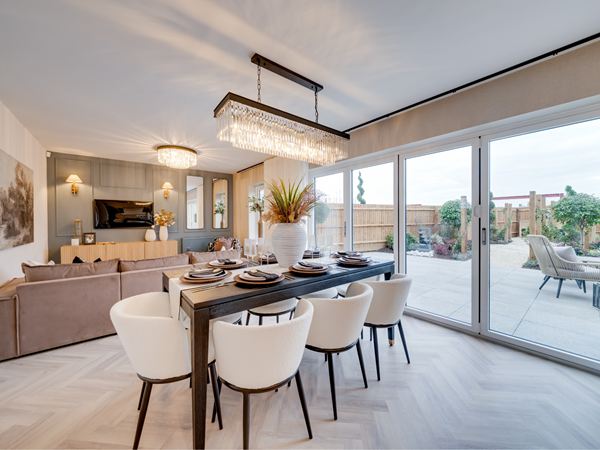 A bright and modern open plan dining room in a Charles Church home, with bifold doors leading to the garden and a cream colour scheme. 