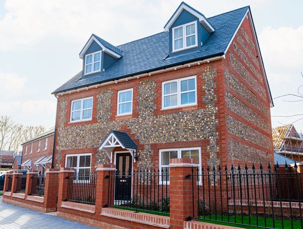 Front view of a three‑storey brick and flint home at Ridge Walk.