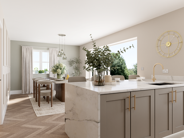 Open-plan kitchen and dining area with a marble island, light gray cabinets, and gold hardware. A wooden dining table with upholstered chairs sits near large glass doors that open to the garden. Natural light floods the space, highlighting the herringbone-patterned wooden floor.