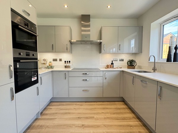 Kitchen with grey cabinets, integrated appliances and wood-effect flooring