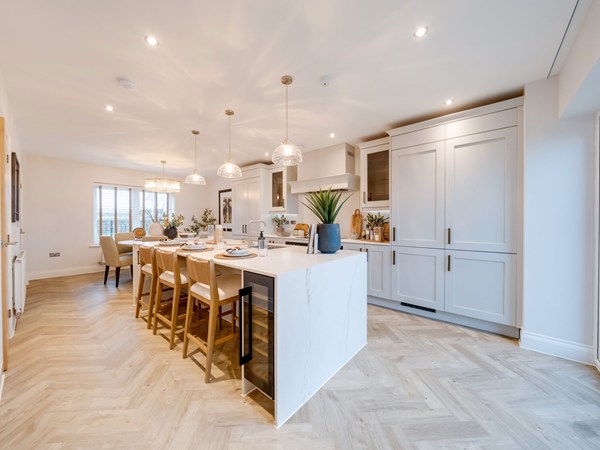 Open-plan kitchen with island, bar stools and herringbone flooring at Heysham.