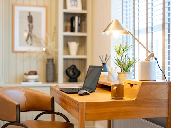 Home office with wooden desk and lamp in a new build home.