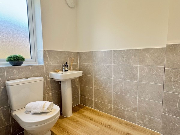 Cloakroom with toilet, pedestal basin and tiled walls