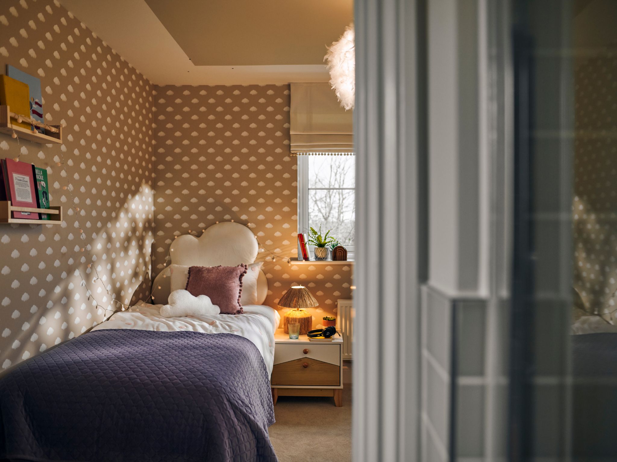 A beautifully decorated kids bedroom in a Charles Church home, with cloud wallpaper. 