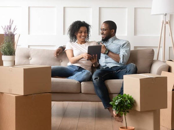 Couple sitting on sofa surrounded by moving boxes