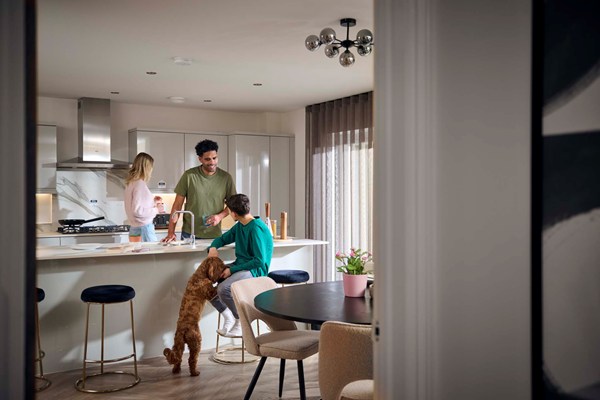 A family and their dog relaxing in the kitchen of their new Charles Church home