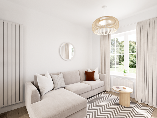 Cozy family area with a light gray sectional sofa, a round wooden coffee table, and a chevron-patterned rug. A circular mirror hangs on the wall, and large windows with light curtains allow natural light to fill the space.