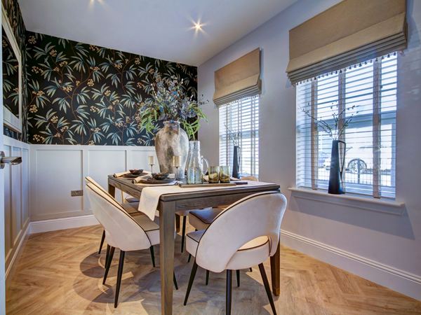 A stunning dining room in a modern new Charles Church home, with leaf wallpaper and wooden floors. 