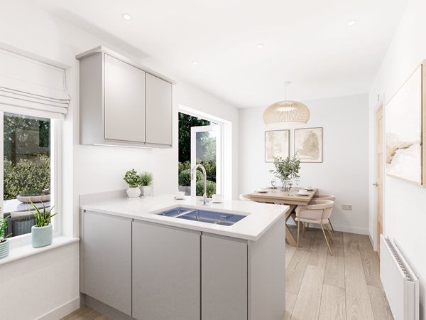 A bright, modern kitchen with light grey cabinets and a white countertop featuring an integrated sink. The space opens into a dining area with a wooden table, four chairs, and a woven pendant light. Large windows and a glass door provide natural light, with greenery visible outside