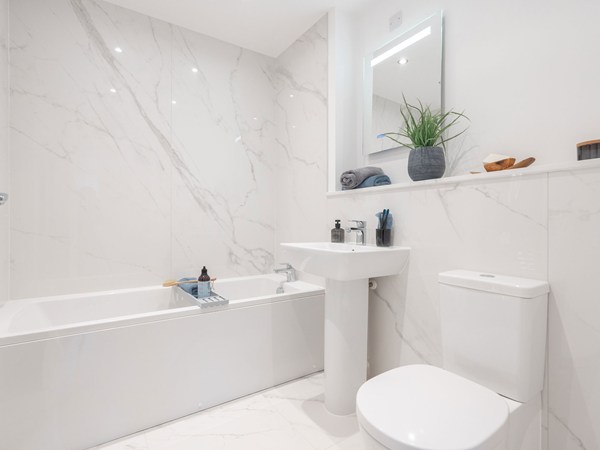 Contemporary bathroom with bath, pedestal sink and marble-effect wall tiles.