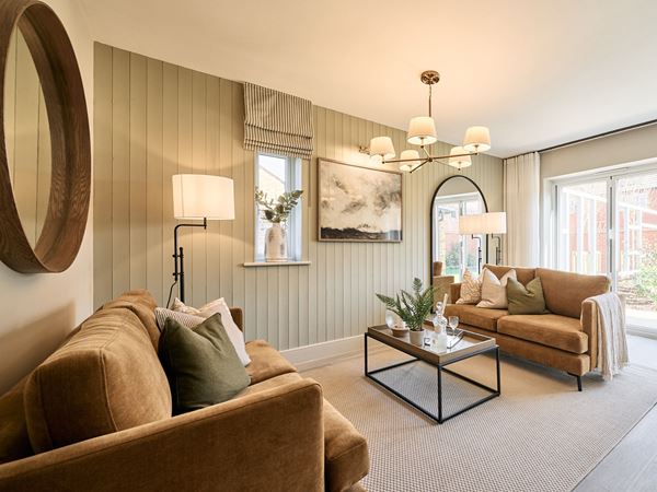 A stunning living room in a Charles Church home with brown sofas and green accents.