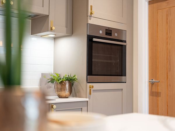 A bright and modern Charles Church kitchen with grey cabinets and integrated AEG appliances.