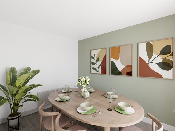 Contemporary dining area with a wooden oval table set for six, featuring green and white plates and glassware. A green feature wall is decorated with three abstract framed artworks, and a large potted plant adds greenery to the corner.